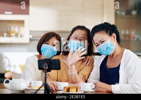 Gruppe von älteren asiatischen Frauen in medizinischen Masken Aufnahme Video Für Abonnenten oder Videoanrufe bei Freunden oder Familienmitgliedern Stockfoto
