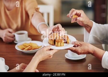 Hände von älteren Frauen essen köstliche traditionelle Mondkuchen, wenn Feiern Mitte Herbst Festival zu Hause Stockfoto