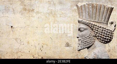 Alte Mauer mit Flachrelief mit assyrischen Kriegern, Persepolis, Iran. UNESCO-Weltkulturerbe. Horizontaler Hintergrund mit geprägtem Bild persisch b Stockfoto