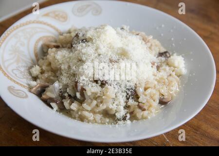 'Risotto ai funghi', gekochtes Reisgericht mit Scheiben von Pilzen mit Parmesan-Käse, in einer weißen Schüssel Stockfoto