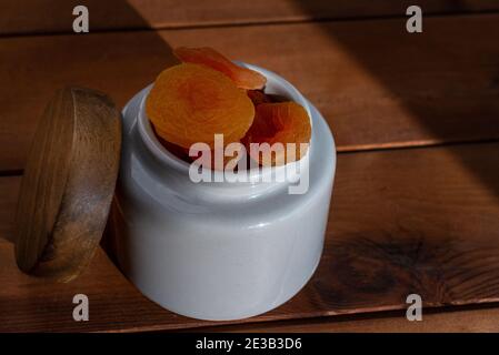 Schüssel mit getrockneten Aprikosen auf Holztisch. Natürliches Sonnenlicht. Gesunde Lebensmittel und Snacks Stockfoto