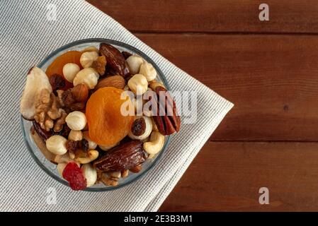 Verschiedene Nüsse und getrocknete Früchte in Schale auf Leinenstoffen. Draufsicht, Platz für Text Stockfoto