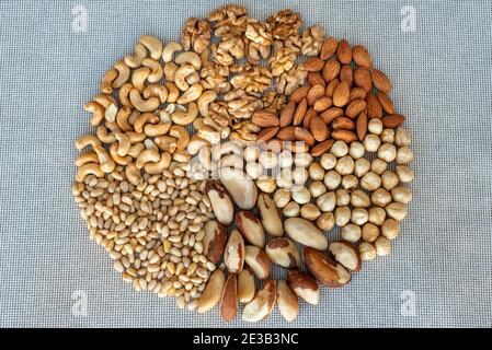 Ein Kreis von verschiedenen Nüssen auf Leinenstoffen, Nahaufnahme. Nüsse Kern aus Walnuss, Haselnuss, Mandel, brasilien, Cashew, Pinienkerne Stockfoto