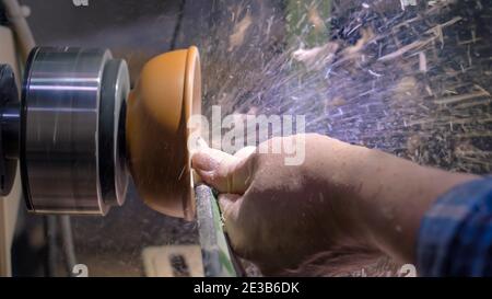 Zimmermann mit Meißel zum Formen von Holzstücken auf der Drehmaschine - Seitenansicht Stockfoto