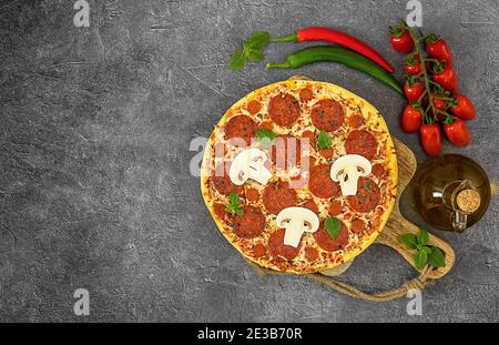 Leckere Pepperoni Pizza und Zutaten zum Kochen Tomaten, Chili, Basilikum auf grauem Hintergrund. Stockfoto