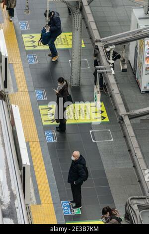 Maskierte Pendler warten auf einem fast menschenleeren Bahnsteig im JR-Hauptbahnhof in Osaka, Japan Stockfoto