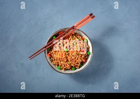 Instant Nudeln mit Essstäbchen, von oben auf einem blauen Hintergrund geschossen Stockfoto