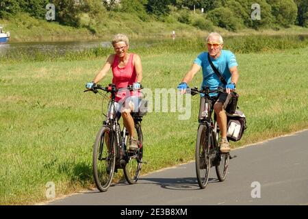 Seniorenpaar Radfahren Sommer Deutschland Urlaub Mann Frau draußen auf einem E-Bike, gesunde Lebensweise Radfahren Deutschland alte Leute Seniorenpaar Lebensstil Stockfoto