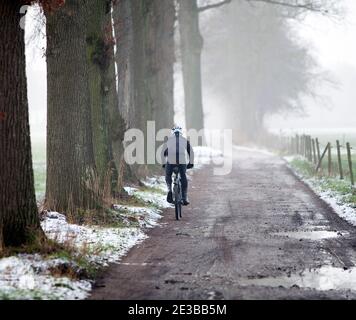 Mann auf Mountainbike-Fahrten im Winter auf Schotterstraße In der Nähe von utrecht in holland Stockfoto