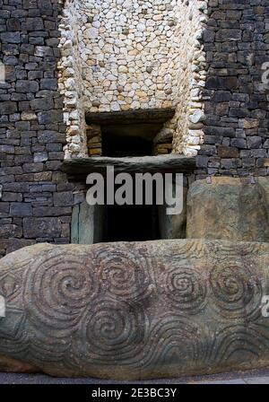 Im Vordergrund befindet sich der berühmte Eingangsstein von Newgrange, mit Spiralen und Lutschern und der berühmten Dreifachspirale. Im Hintergrund die Tür und r Stockfoto