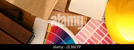 Auf dem Tisch steht ein Harthut, bunte Palette mit Mustern, Lineal, Holzteil und Decke. Stockfoto