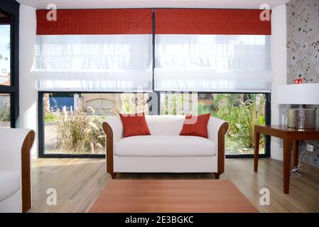 Minimalistisches weißes Wohnzimmer und Interieur mit weißem Sofa oder Sofa & Weiße Fensterläden Stockfoto