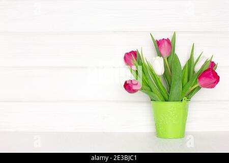 Tulpe Blumenstrauß in Eimer auf Holztisch in der Nähe weiß lackierten Holzbrett Wand. Speicherplatz kopieren. Frühling rustikalen Hintergrund Stockfoto