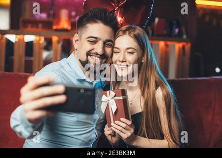 Kaukasische Paar feiern Valentinstag halten Ballons und machen Ein Selfie mit einem Telefon Stockfoto