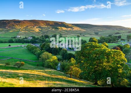 Landschaftlich sonniges Burnsall Dorf im River Wharfe Tal (Hanglagen, Hochmoor, grüne Felder, Weiden, blauer Himmel) - Yorkshire Dales, England, Großbritannien Stockfoto