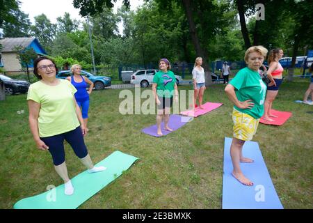 Gruppe von Frauen mittleren Alters, die morgens Stretching-Übungen im Stadtpark machen. Juli 2020. Kiew, Ukraine Stockfoto