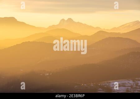 Pedraforca (Mitte) und Rasos de Peguera (rechts) bei Sonnenuntergang mit Sant Joan de les Abadesses (El Ripollès) unten Stockfoto