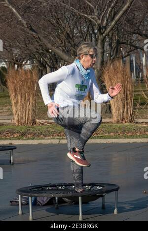 Eine Frau in einer Rebounding-Klasse, die kräftige Bewegungen beim Springen auf einem kleinen Trampolin kombiniert. In Flushing Meadows Corona Park in Queens, NYC. Stockfoto