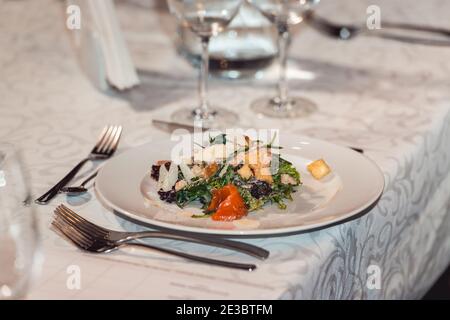 Köstlicher Salat mit Lachs und Garnelen in einem Restaurant zum Essen und Wein. Kleine Portion auf einem weißen Teller. Stockfoto
