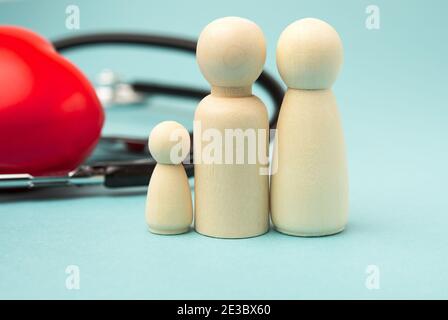 Familie von Holzfiguren von Männern auf Hintergrund von rotem Herz und Stethoskop, Krankenversicherungskonzept, Nahaufnahme Stockfoto