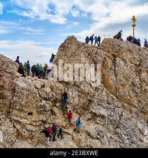 Garmisch-Partenkirchen, Gemany, 5. August 2019: Unerfahrene Touristen ohne Sicherheit besteigen den Gipfel der Zugspitze mit dem Gipfelkreuz Stockfoto