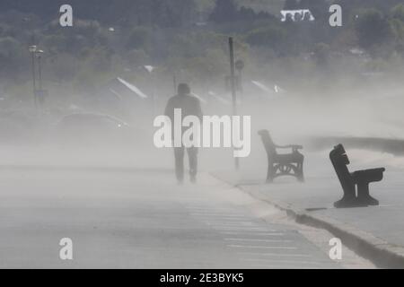 Schottland, Ayrshire, Ayr, Mann, der auf der Promenade läuft, während Sand vom Strand geblasen wird Stockfoto