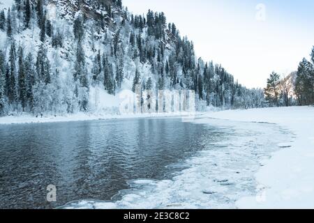 Eisige Ufer des Sees mit verschneiten Wald. Kaltes Wetter, gefrorenes Flussbett aufgrund von scharfem Kälteeinbruch Stockfoto