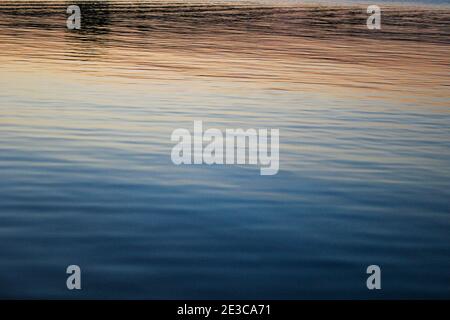 Der Sonnenuntergang spiegelte sich in der ruhigen stillen See in Oliva, Spanien Stockfoto