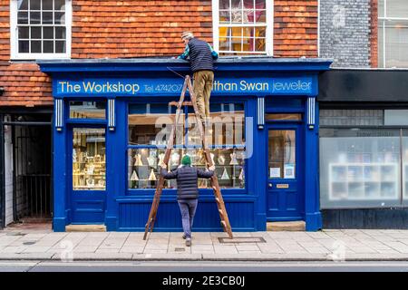 Eine Frau hält EINE Leiter für einen älteren Mann, der Immobilien baut, Lewes, East Sussex, Großbritannien. Stockfoto