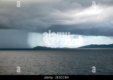 Regenmauer über dem Atlantischen Ozean und einer Karibikinsel Stockfoto