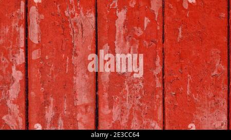 Alte Holzbretter mit roter abblätternder Farbe mit Rissen. Raue Oberflächenstruktur. Stockfoto
