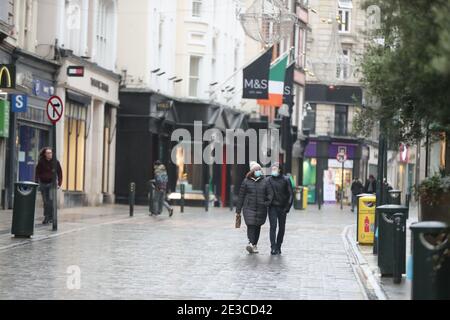 Die Menschen laufen entlang einer verlassenen Grafton Street im Stadtzentrum von Dublin, während Irland in der Sperre bleibt, um die Ausbreitung des Coronavirus zu verhindern. Irlands Gesundheitswesen steht möglicherweise vor der schwierigsten Woche seiner Geschichte: Die Zahl der Covid-19-Patienten, die eine Intensivbehandlung benötigen, ist seit Ende Dezember stark gestiegen. Bilddatum: Montag, 18. Januar 2021. Stockfoto