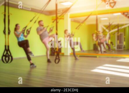 Das Gruppentraining mit einem Trainer in der TRX-Scharnierhalle führt eine Übung durch: Arme, Sonne, Kopierraum, Fitnesscenter Stockfoto