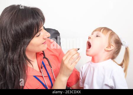 Arzt Kinderarzt untersucht den Hals eines kleinen Mädchens, das eine Halsschmerzen hat. Behandlungskonzept für Halsschmerzen, verursacht durch Infektion und Mandelentzündung Stockfoto