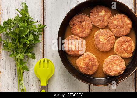 Fleischschnitzel auf einer alten Bratpfanne Nahaufnahme auf einem Holztisch Stockfoto