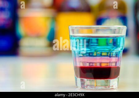 Ein farbenfrohes Getränk in mehreren Schichten, das auf einer Bar zubereitet wird, die vom Barkeeper zubereitet wird. Party Time Stockfoto