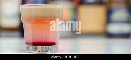 Ein farbenfrohes Getränk in mehreren Schichten, das auf einer Bar zubereitet wird, die vom Barkeeper zubereitet wird. Party Time Stockfoto