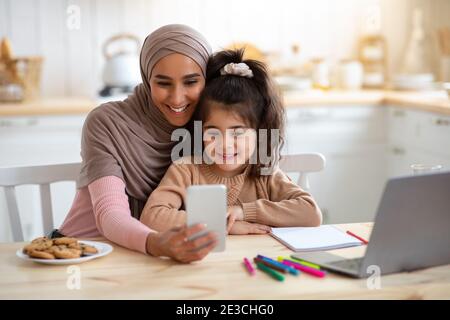 Selfie-Spaß. Happy Muslim Frau Foto Mit Kleinen Tochter Auf Smartphone Stockfoto