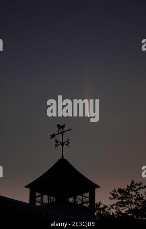 2020's comet NEOWISE above the weather vane on an old barn in the pre-dawn sky of July. Stockfoto