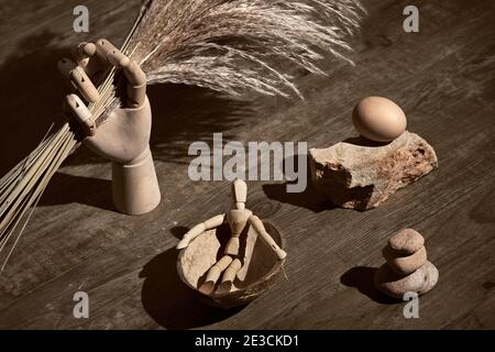 Menschliche Figur im Boot aus Kokosnussschale. Holzmodell Hand hält trockene Pampas Gras. Surreale Dekorationen, Türme aus Zen-Stein. Vintage, Retro grange Stockfoto