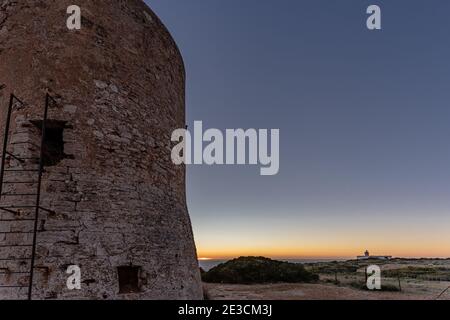 Bild des Cap Blanc Wachturms auf Mallorca mit dem Leuchtturm im Hintergrund bei Sonnenuntergang.dieser Turm wurde in den XVI warnte vor Piratenangriffen. Stockfoto