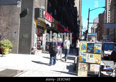 Menschen, die in New York, USA, auf einer Straße spazieren gehen Geschenke Tasche Taschen Bücher Buchwerbung Schilder Plattentopf Pflanzen Blumen Blumenladen Geschäfte vor dem Fußweg Stockfoto