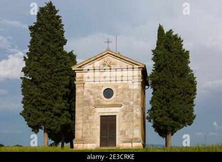 Alte Kirche von Vitaleta mit Bäumen auf beiden Seiten in San Quirico d'Orcia, in der Nähe von Pienza, Toskana, Italien im Mai - Kapelle der Madonna di Vitaleta Stockfoto