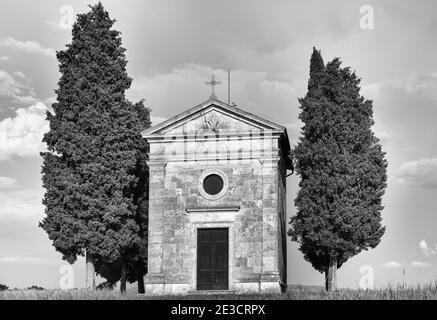 Alte Kirche von Vitaleta mit Bäumen auf beiden Seiten in San Quirico d'Orcia, in der Nähe von Pienza, Toskana, Italien im Mai - Kapelle der Madonna di Vitaleta Stockfoto