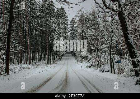 Gefährliche Strecke der Straße mit Schnee und Eis bedeckt.Snowy Straße Durch Wald.Winterpanorama.Fahren in eisiger gefrorener Landschaft.Schlechtes Wetter.S Stockfoto