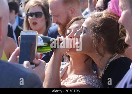 Ayr Rennbahn, Ayr, Ayrshire Schottland, Großbritannien. Mann, der ein Handy benutzt, um zwei Mädchen zu fotografieren, die sich eine Flasche teilen Stockfoto