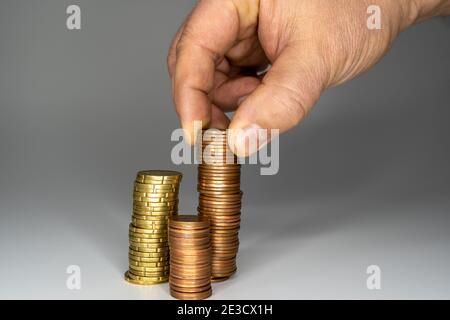 Man's Hand legte Geld Münzen zu Stapel von Münzen. Konzept für Geld, Finanzen, Unternehmenswachstum. Stockfoto