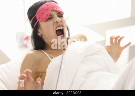 Frau schreit im Liegen auf dem Bett Stockfoto