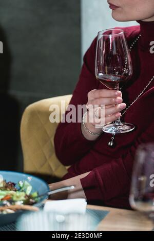 Frau hält ein Glas Rotwein. Menschen betrachten die Farbe des Weines und versuchen, wie es in verschiedenen Gläsern riecht Stockfoto