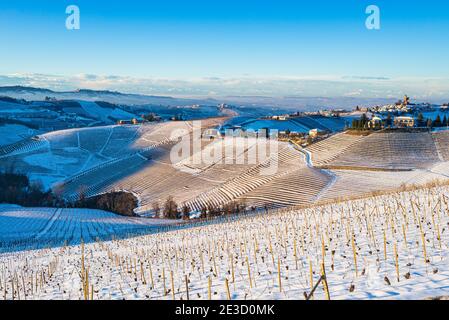 Italien Piemont: Weingärten einzigartige Landschaft Winter Sonnenuntergang, Serralunga d'Alba mittelalterlichen Dorf Burg auf einem Hügel, die Alpen schneebedeckten Berge backg Stockfoto